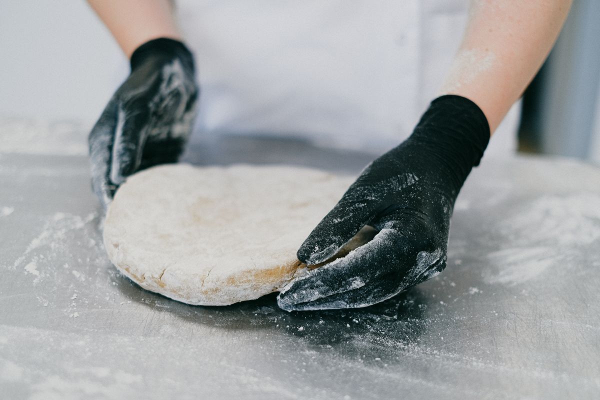 Banketbakker die deeg kneedt in de bakkerij